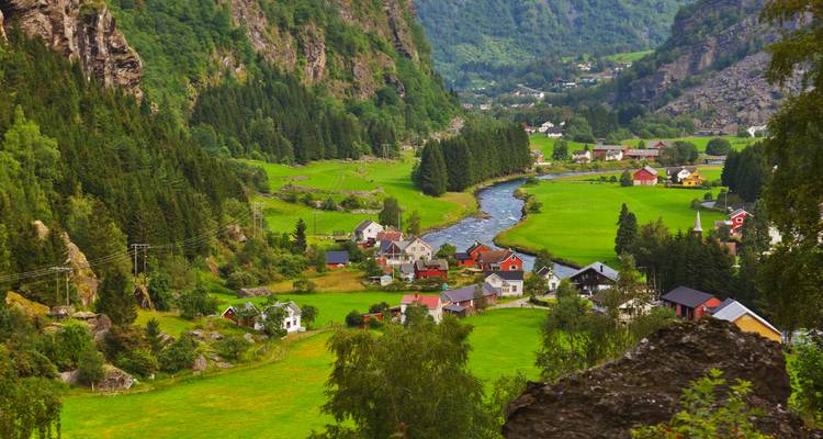Verdant river valley town nestled among steep forested mountains in western Norway.