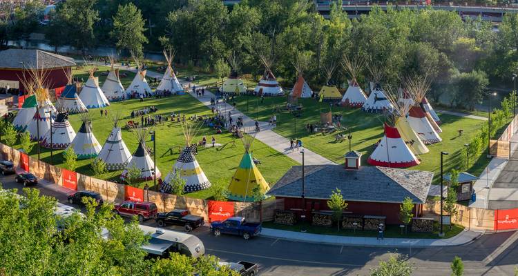 Bird’s-eye view of a field filled with colourful tipi tents and visitors during a cultural festival.