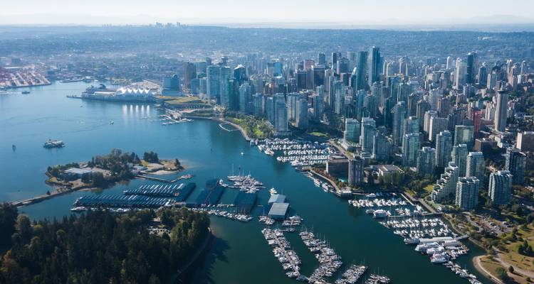 Aerial panorama of Vancouver’s downtown towers, marina and Stanley Park beside the sparkling harbour.