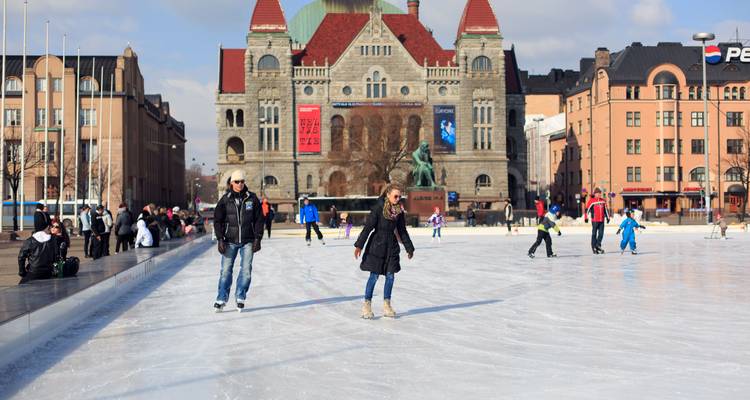 Locals and visitors ice skating on an outdoor rink in front of Helsinki’s National Theatre.