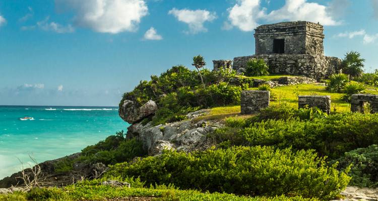 Petit temple en pierre perché sur une falaise herbeuse dominant les eaux turquoise des Caraïbes et le récif de corail.