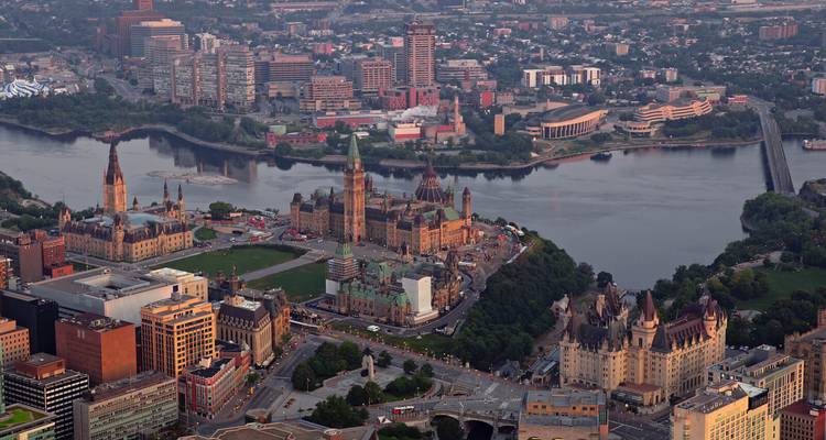 Vue aérienne au crépuscule du complexe de la Colline du Parlement d'Ottawa et du paysage urbain environnant à côté de la rivière des Outaouais.