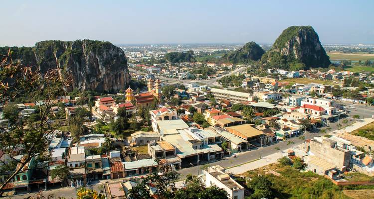 Elevated view over sprawling Vietnamese town nestled between limestone outcrops and farmland.