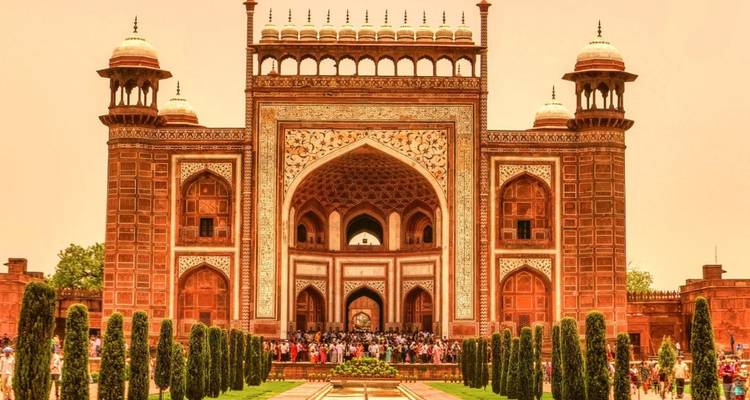 Verfraaide zandstenen poortingang naar het Taj Mahal complex met bezoekers