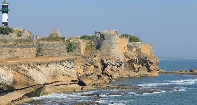 Historic seaside fort with lighthouse perched on rocky cliffs overlooking the Arabian Sea.