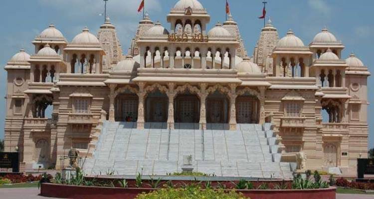 A grand marble Hindu temple with domes and intricate columns under a blue sky.