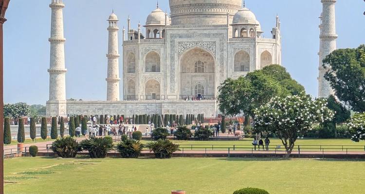 Clear view of the Taj Mahal framed by green gardens and visitors walking along the pathways