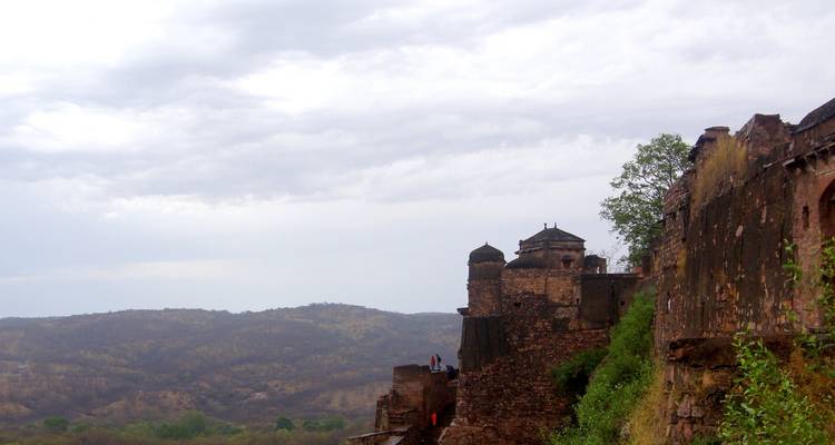 Ranthambore Fort’s ancient ramparts perch on a rocky ridge overlooking rolling countryside under cloudy skies.
