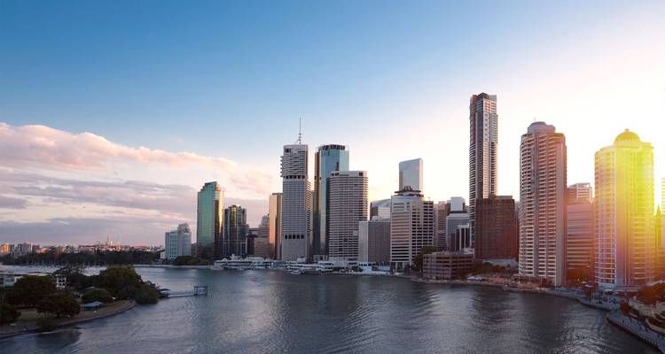 De moderne skyline van Brisbane langs de rivier glint in het warme avondlicht boven de Brisbane River.
