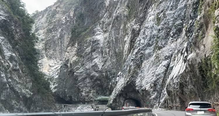 Steile Marmorkliffe, die sich über eine gewundene Bergstraße und einen Tunnel erheben.