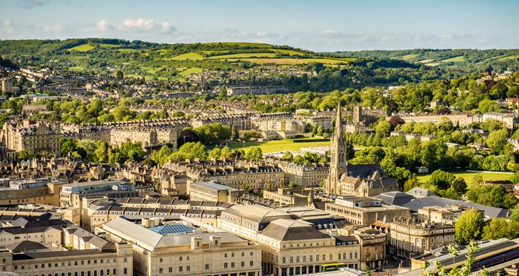 Vue panoramique depuis une colline surplombant la ville de Bath avec la campagne verte vallonnée au-delà.