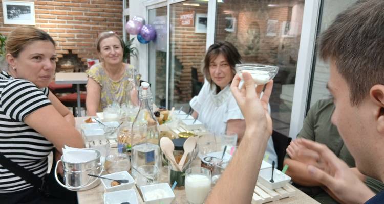 Petit groupe assis autour d'une table dégustant du yaourt et des collations locales à l'intérieur