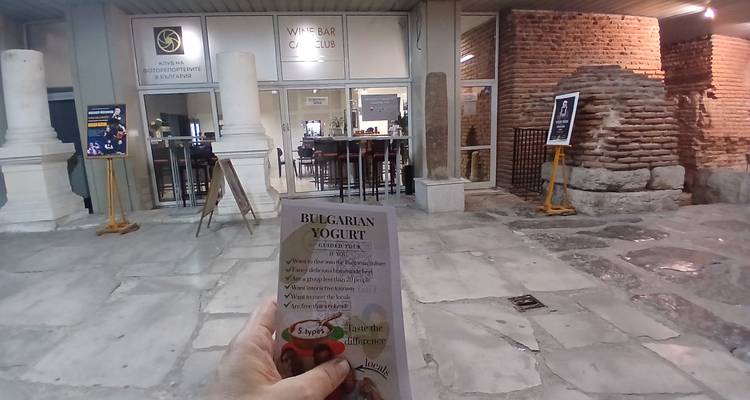 Une main tenant un dépliant de yaourt bulgare à l'extérieur de l'entrée d'un bâtiment historique la nuit