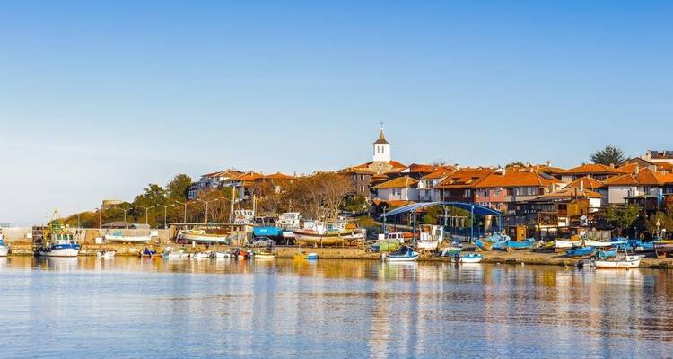 Charmante ville côtière pittoresque avec des maisons aux toits en terre cuite et de petits bateaux de pêche sur une eau bleue calme.