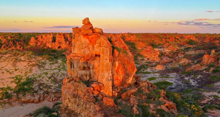 Dramatic red sandstone pinnacle and rugged terrain glowing in soft sunset light in Australia’s Kimberley.