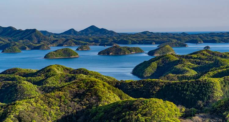Panoramic view of emerald islands scattered across a calm blue sea under clear sky.