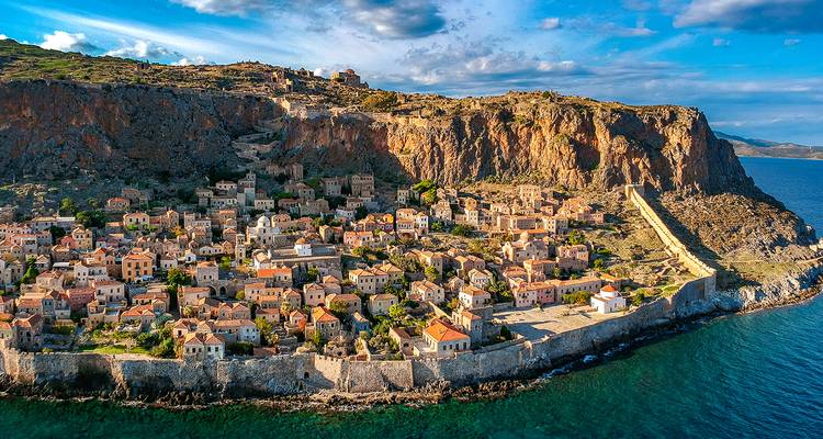 Aerial view of a fortified medieval town perched on a rocky peninsula surrounded by turquoise sea.