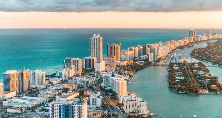 Vue aérienne du coucher de soleil à Miami Beach montrant un ruban de complexes hôteliers de grande hauteur bordant l'océan Atlantique et les voies navigables Intracoastal.