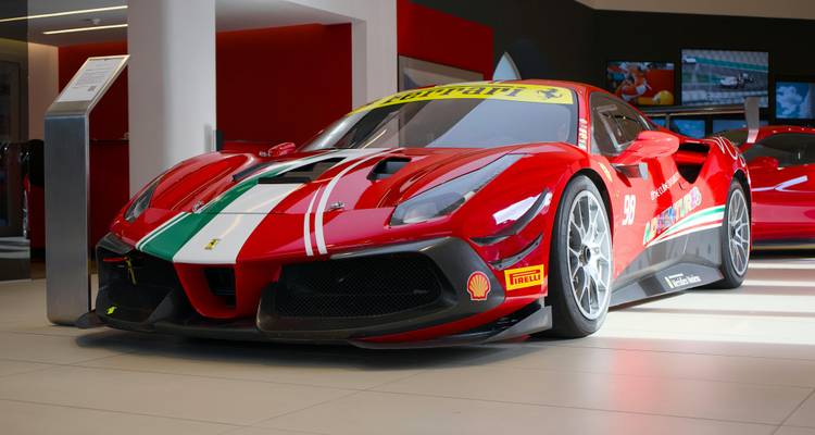 Slank rode Ferrari raceauto met Italiaanse tricolore strepen tentoongesteld in een moderne showroom.