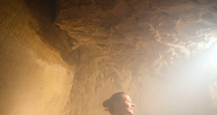 Steamy cave interior with soft light illuminating a relaxed woman.