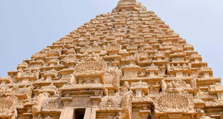 Upward view of the intricately carved Brihadeeswarar Temple tower against a clear sky.