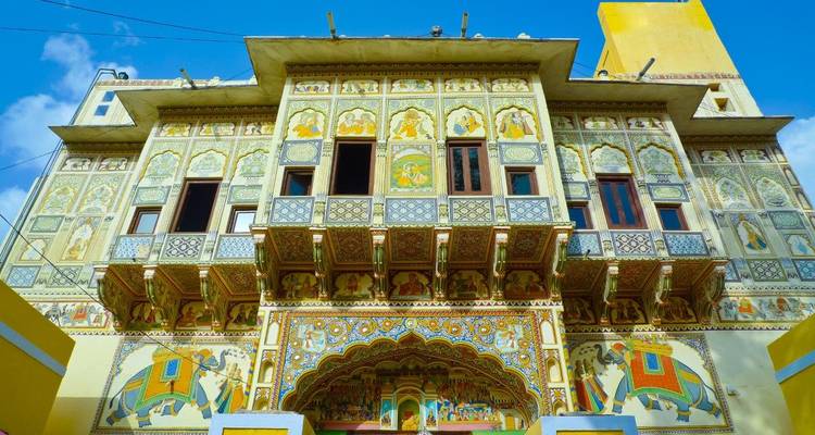 Colorful frescoed haveli façade with ornate balconies in Shekhawati region.