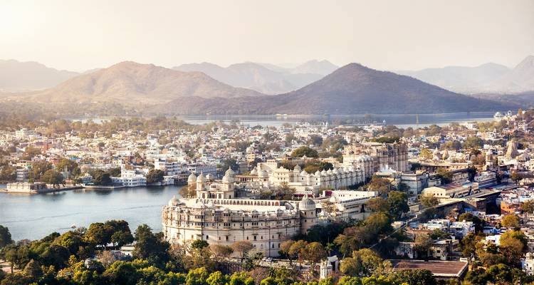 Panoramic view of Udaipur City Palace complex beside Lake Pichola and surrounding hills.