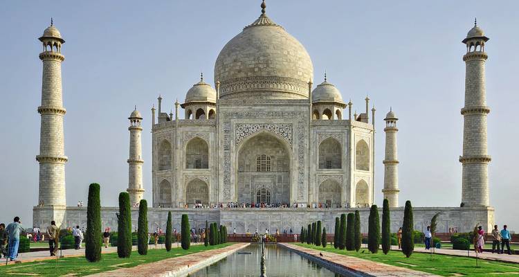 Front view of the iconic Taj Mahal with reflecting pool and visiting crowds.