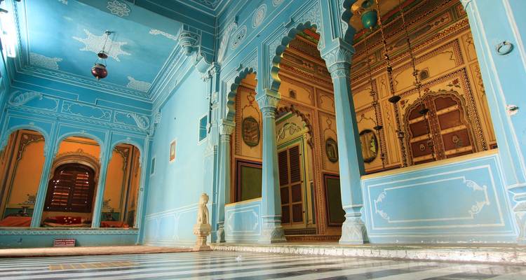 Ornate blue interior hall with arched doorways and painted ceilings in Rajasthan palace.
