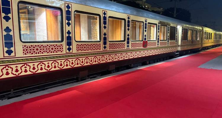 Exterior view of the Palace on Wheels luxury train alongside a red carpet at the station.
