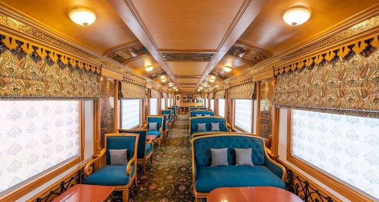 Long saloon car of the Palace on Wheels with patterned drapes, teal armchairs and ornate ceilings.