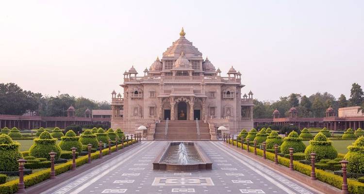 Symmetrical Akshardham Temple complex framed by manicured gardens and a central fountain at dawn.