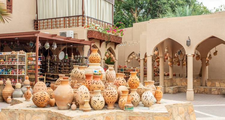 Ausstellung traditioneller Tonkrüge auf einem Innenhof eines Freiluftsouks mit Käufern im Hintergrund.