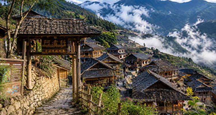 Pintoresco pueblo en la ladera con casas de madera y un valle lleno de niebla en Yunnan.