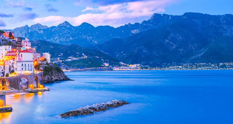 La tombée du jour s'installe sur la côte d'Amalfi avec des montagnes encadrant une baie bleue sereine.