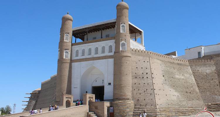 Historic Ark fortress with twin towers and ramp in bright blue Uzbek sky.