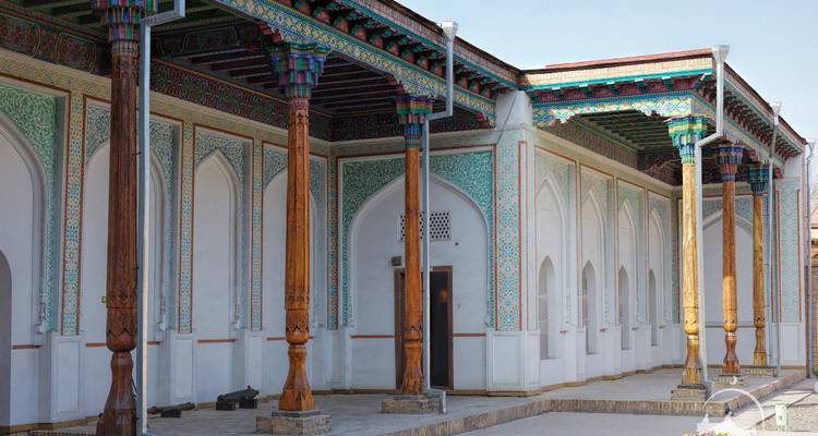 Long wooden columns and intricately painted ceilings of a historic palace veranda.