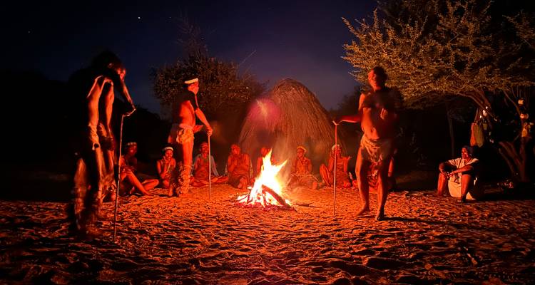 Traditional bushmen community gathered around a fire performing rituals at night