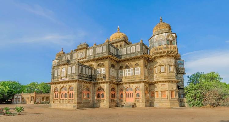 Elegant historic palace with domes and intricate windows against a bright blue sky