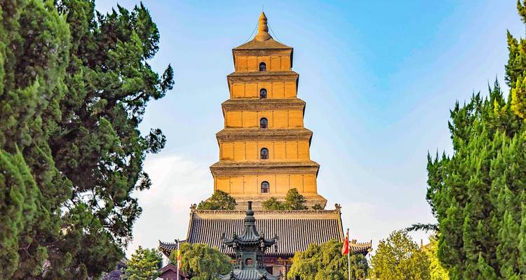 Impressive multi-storey Big Wild Goose Pagoda framed by leafy trees against a clear sky
