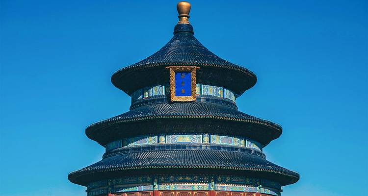 Dark blue tiled circular roof of Beijing’s Temple of Heaven set against a vivid blue sky