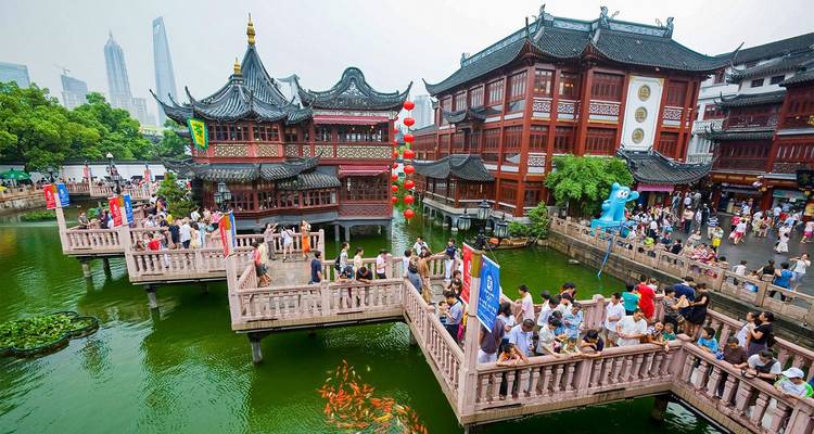 Crowds wander traditional red wooden pavilions and bridges over a koi pond in Shanghai’s old town