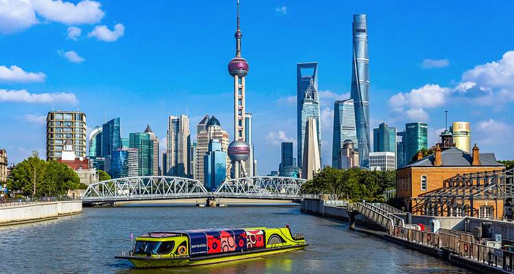 Colorful tour boat cruises past Shanghai’s futuristic skyline of iconic skyscrapers under a bright blue sky