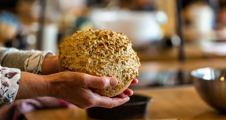 Las manos sostienen un pan de soda irlandés tradicional recién horneado en la cocina de una clase de cocina