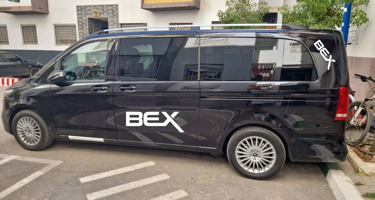 Black Mercedes van branded 'BEX' parked on a residential street with bicycle beside it.