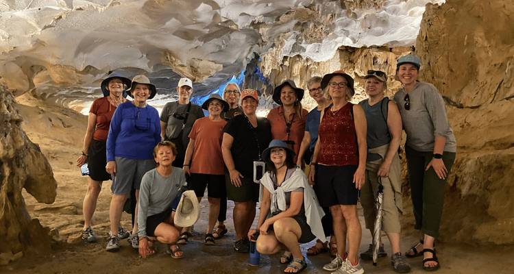 Große Touristengruppe posiert in einer beleuchteten Kalksteinhöhle mit strukturierter Decke in der Ha-Long-Bucht