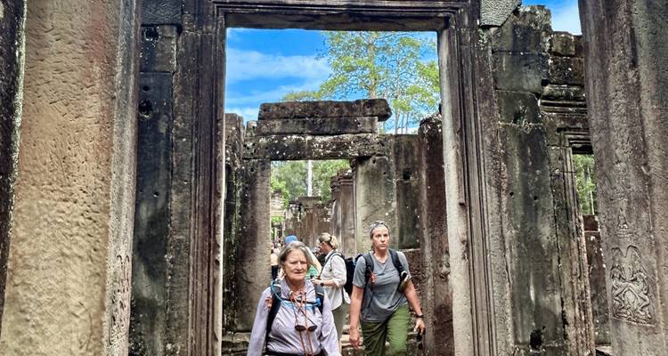 Reisende gehen durch Steintor-Ruinen des Angkor-Tempdelkomplexes unter hellem Himmel