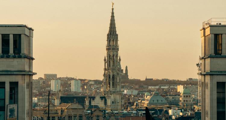 La silhouette de la ville dominée par la haute flèche gothique de l'Hôtel de Ville de Bruxelles aux teintes du coucher de soleil.