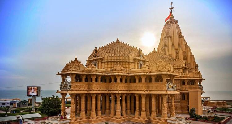 Der golden leuchtende Sandstein-Tempel von Somnath, erleuchtet durch tiefe Sonnenstrahlen mit dem Meer im Hintergrund