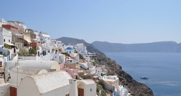 Casas encaladas con cúpulas azules bajando en cascada por los acantilados de Santorini con vistas al mar Egeo.